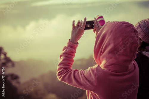 woman hiker taking photo with smart phone at mountain peak