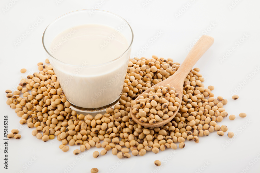 Soy milk in glass with soybeans and wooden spoon Soy milk in glass with soybeans and wooden spoon