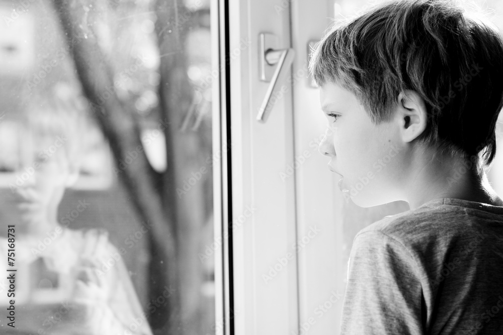 Cute 6 years old boy looking through the window Cute 6 years old boy looking through the window