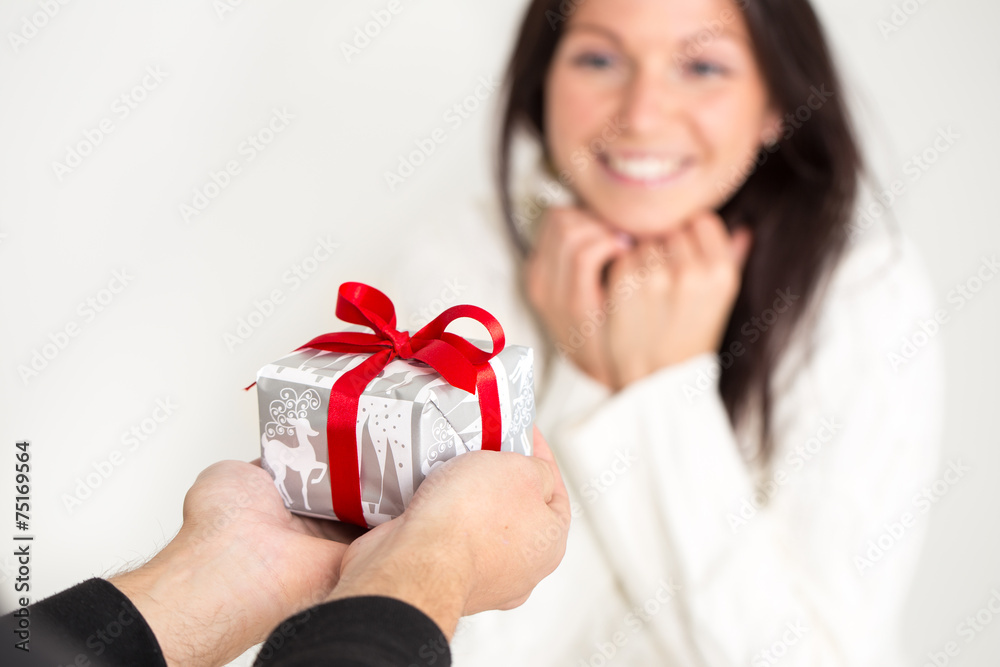 Man giving a Christmas gift to a beautiful young woman .