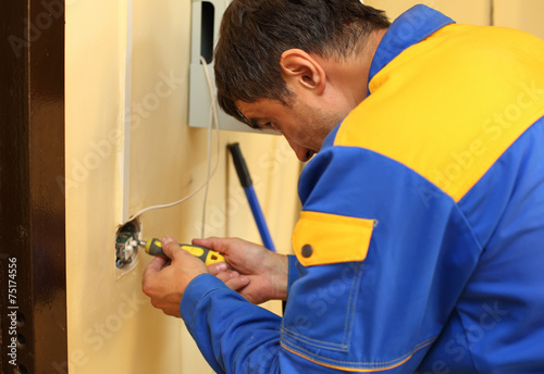 Electrician stripping electrical wires wall socket