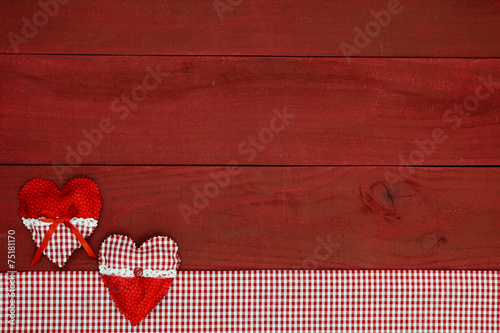 Red hearts by gingham fabric border on wood background
