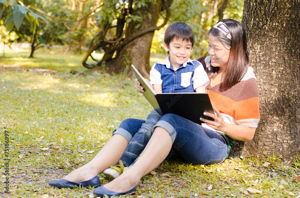 Mother and son read a book together in the park Mother and son read a book together in the park