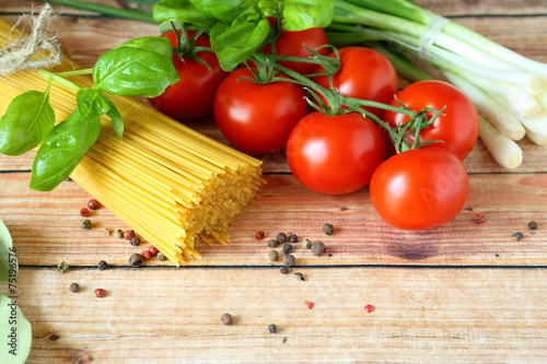 spaghetti, basil and tomatoes on wooden background