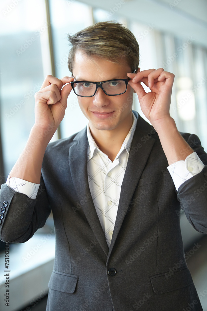 young businessman with glasses standing in the hallway young businessman with glasses standing in the hallway