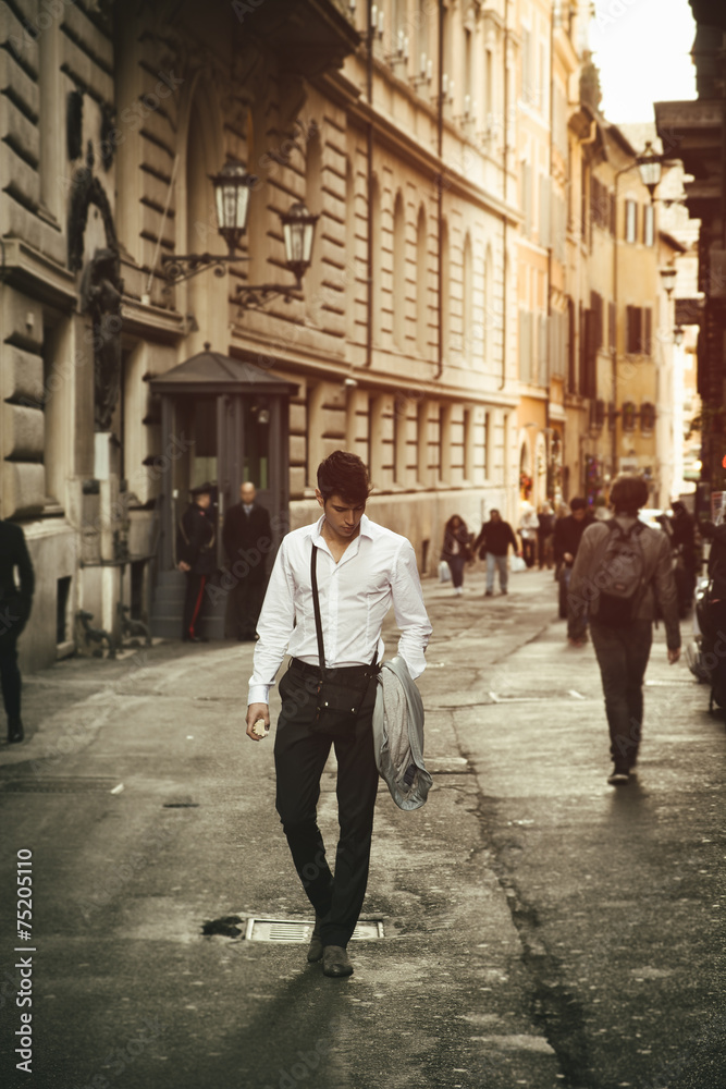 Handsome young man walking in European city street