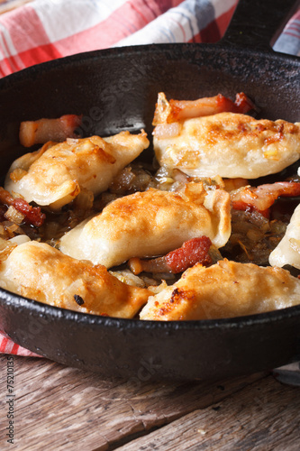 hot fried dumplings with bacon and onions in a pan, vertical