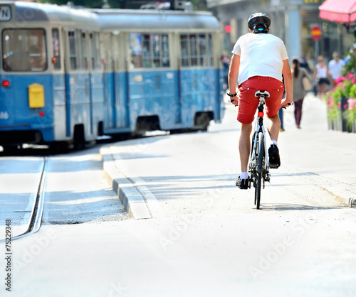 Bike commuter and tram in sunlit city