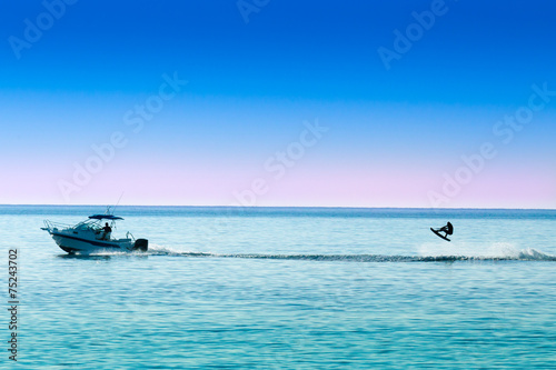Photos silhouette of motor boat and wakeboarder jumping crazy trick