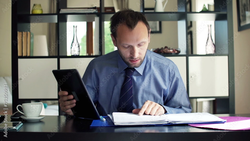 Young businessman chatting on tablet and reading documents Young businessman chatting on tablet and reading documents