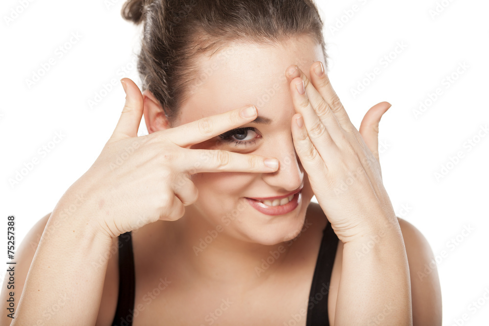 shy woman covering the eyes and looking through her fingers shy woman covering the eyes and looking through her fingers