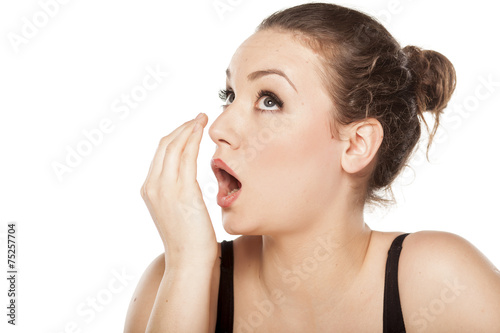 young woman checking her breath with her hand photo