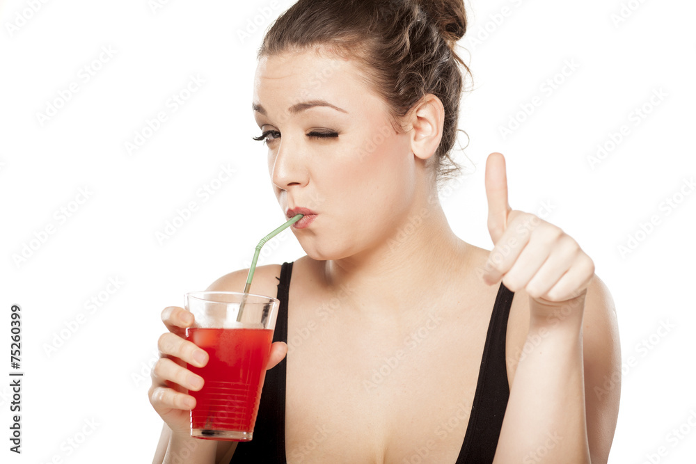 young woman drinking a cocktail and showing thumbs up young woman drinking a cocktail and showing thumbs up