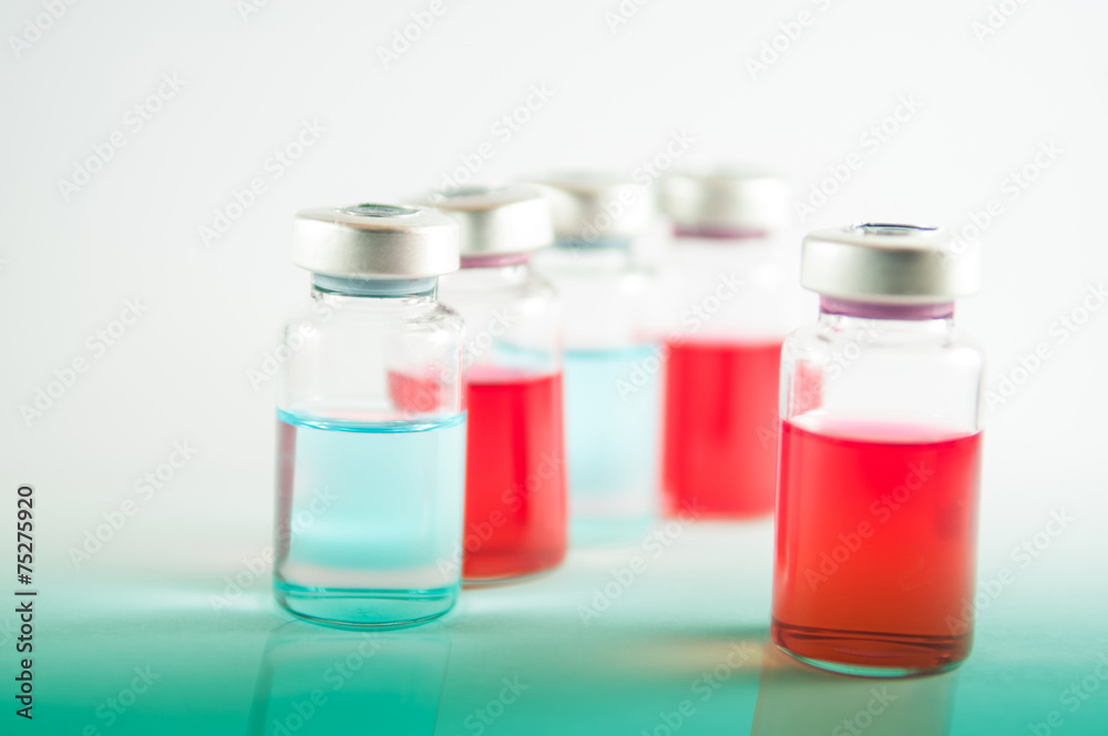 Red and blue liquid in injection vials on red floor effect Red and blue liquid in injection vials on red floor effect