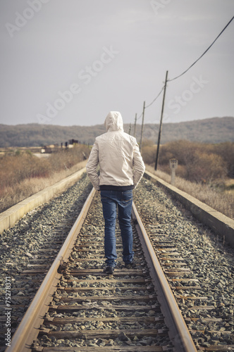 Young man walking on a railway. Rural setting