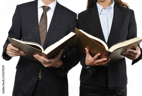 難しい本を読んで調べている男女の二人のビジネスマン