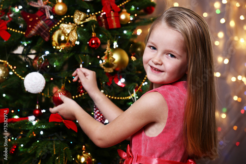 Little girl decorating Christmas tree on bright background © Africa Studio