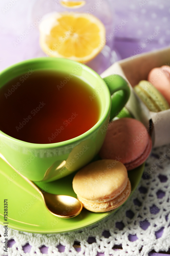 Colorful macaroons with cup of tea on wooden background Colorful macaroons with cup of tea on wooden background
