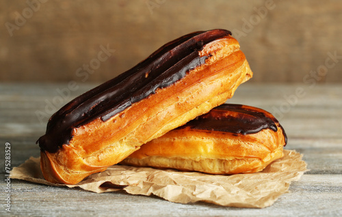 Fotografia Tasty eclairs on wooden table, close up