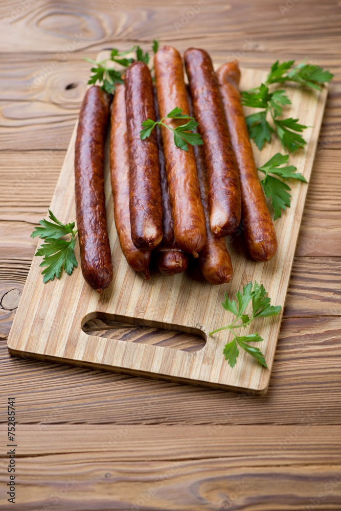 Wooden chopping board with sausages, studio shot Wooden chopping board with sausages, studio shot