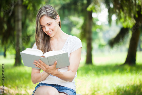Young smiling woman reading a book