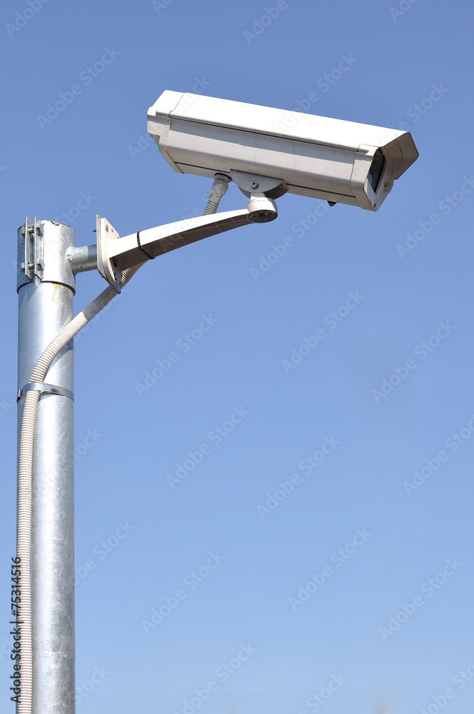 White security camera monitor on iron pole. White security camera monitor on iron pole.