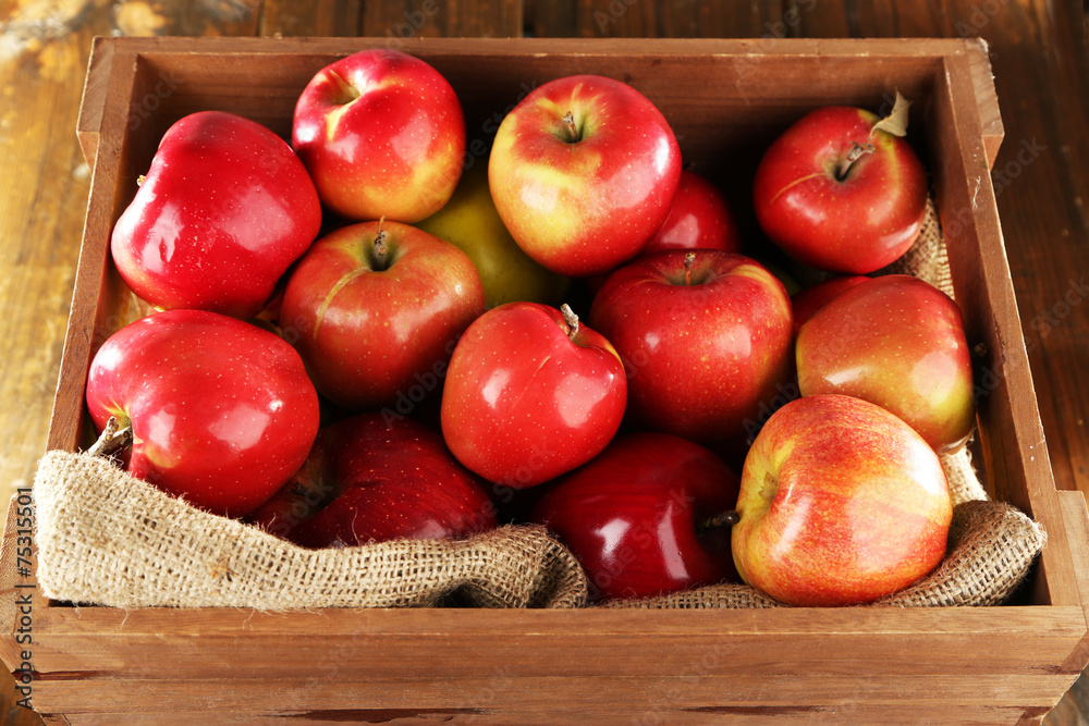 Red apples in wooden crate with burlap cloth