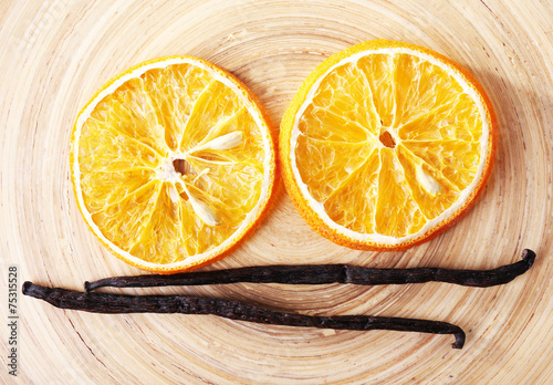 Dried slices of orange with vanilla beans on wooden background