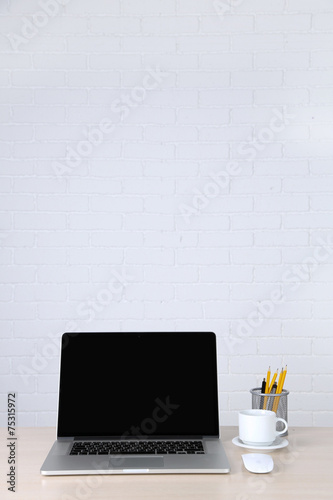 Modern laptop on table, on white wall background