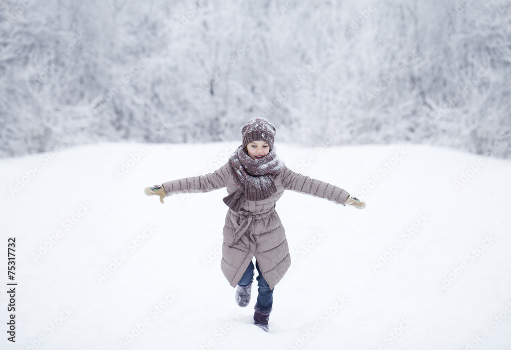 Happy little girl running on the background of snow covered wint Happy little girl running on the background of snow covered wint
