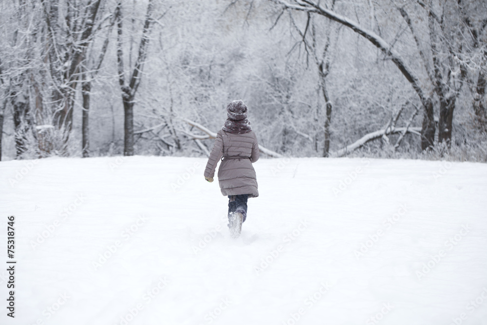 Happy little girl running on the background of snow covered wint
