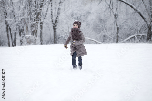 Happy little girl running on the background of snow covered wint
