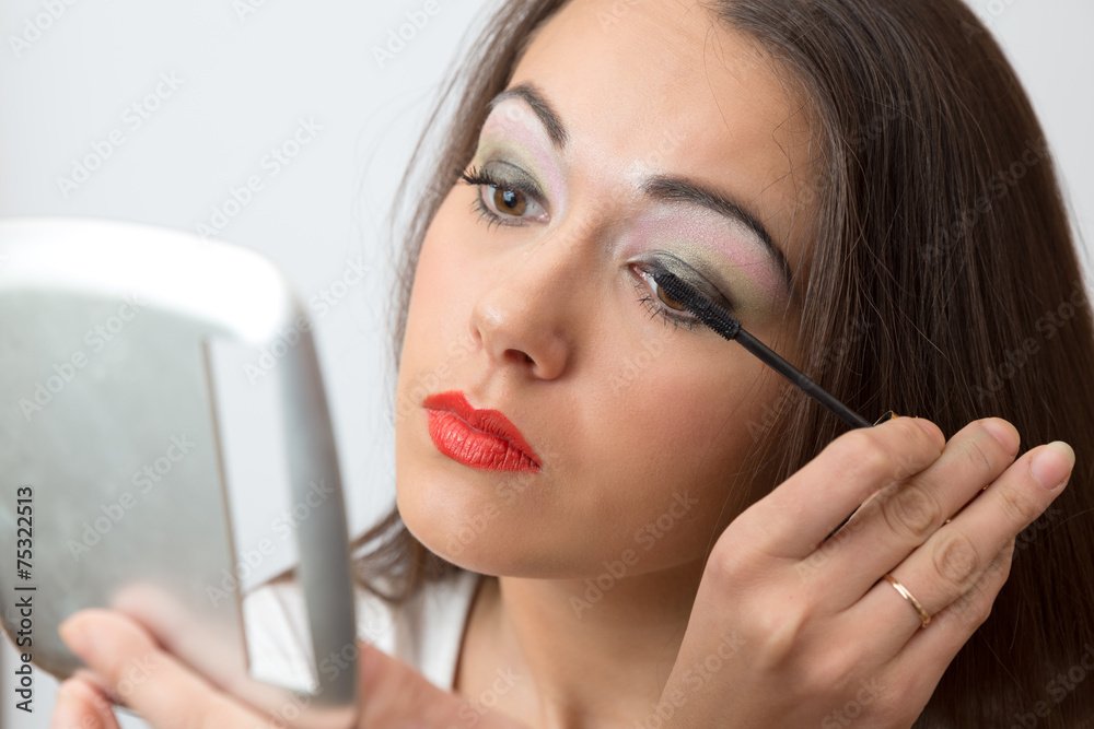 Brunette paints eyelashes mascara in the mirror closeup Brunette paints eyelashes mascara in the mirror closeup