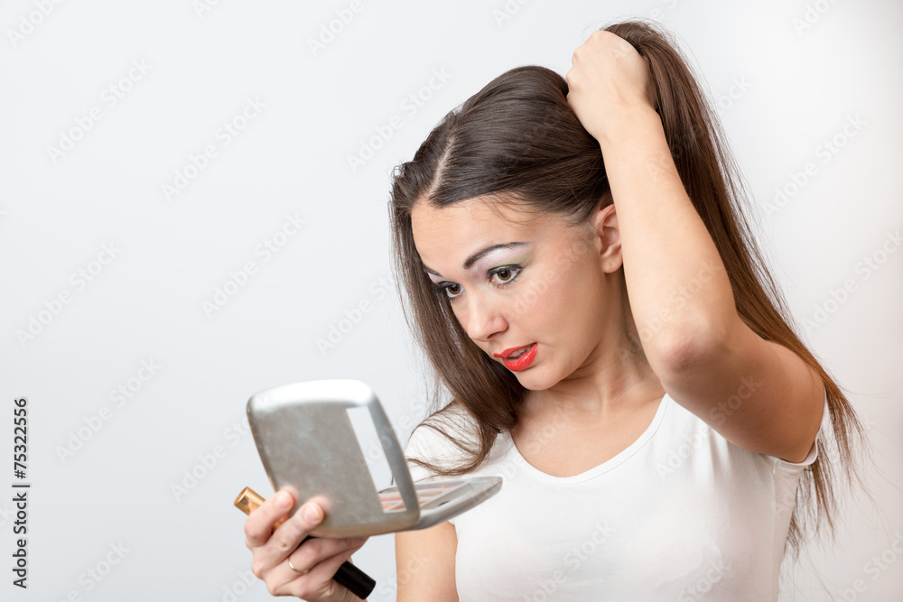 Brunette smiling in front of the mirror doing her long hair Brunette smiling in front of the mirror doing her long hair
