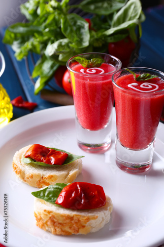 Gazpacho soup in glasses, on color wooden background