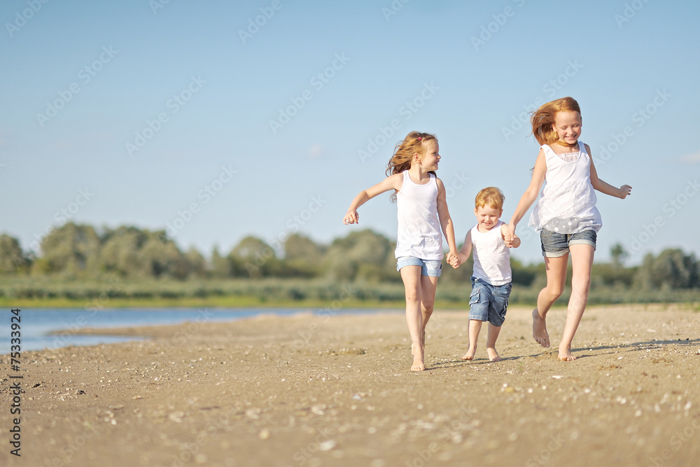 three children playing on beach in summer