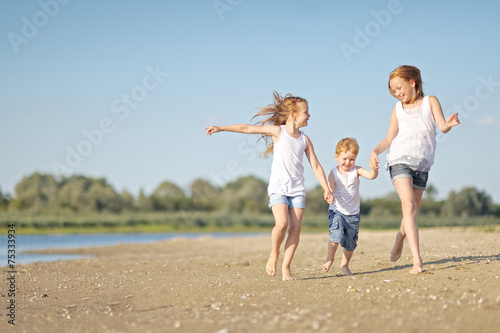 three children playing on beach in summer