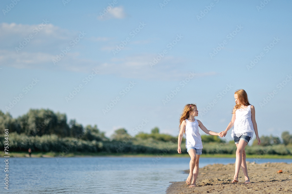 portrait of two sisters walking on the beach