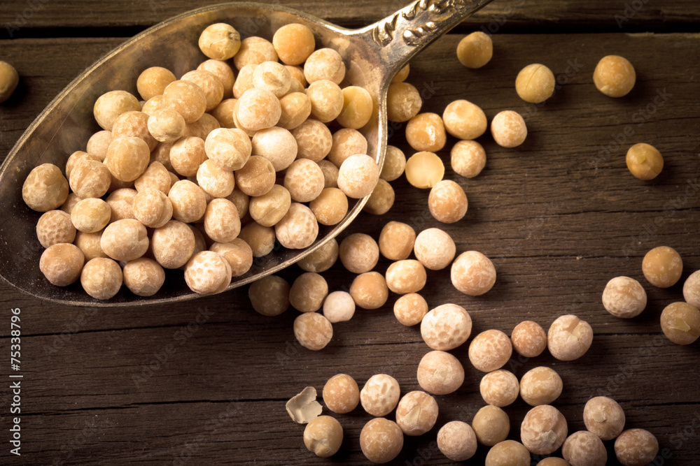 dry peas in a silver spoon on a wooden table. tinted dry peas in a silver spoon on a wooden table. tinted