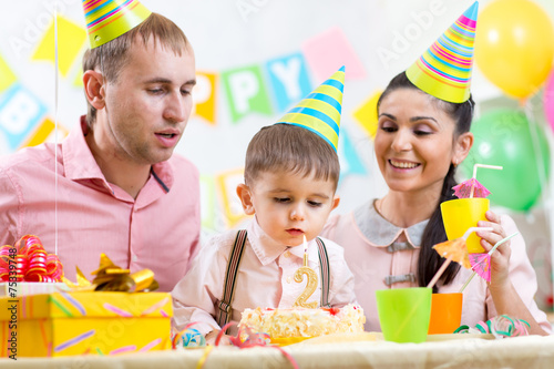 kid with family blowing candle on birthday cake