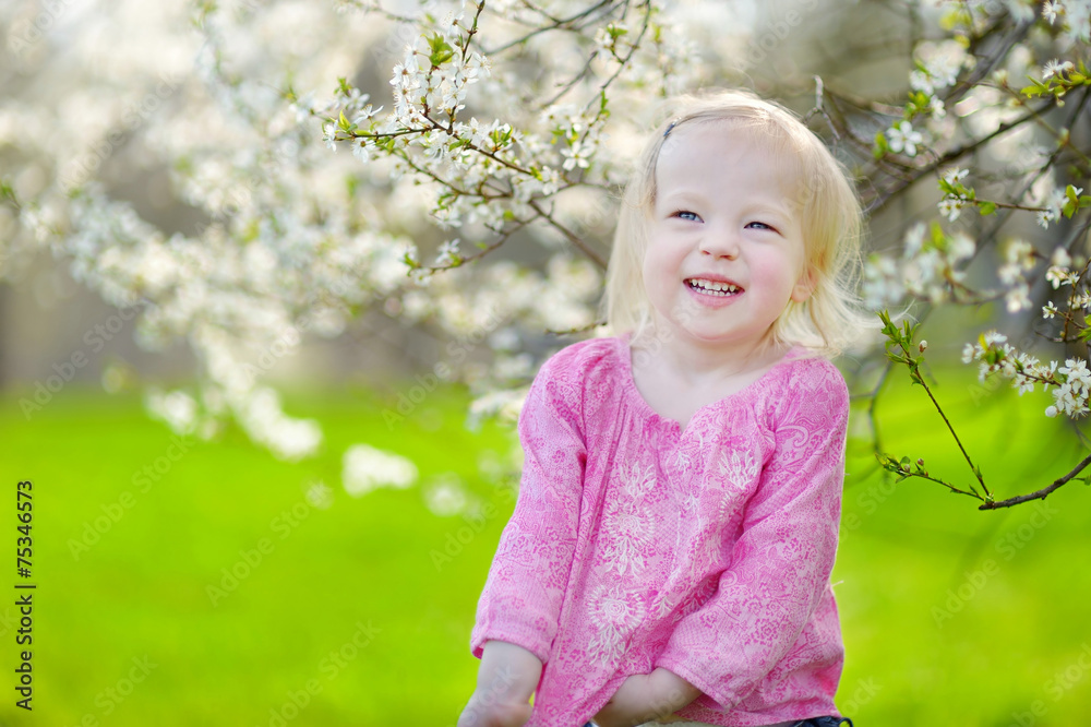 Adorable toddler girl in blooming cherry garden Adorable toddler girl in blooming cherry garden