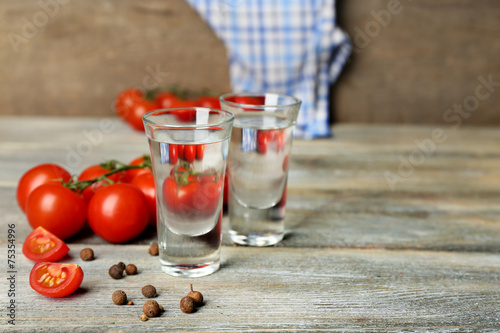 Glasses of ouzo and tomatoes on wooden table photo