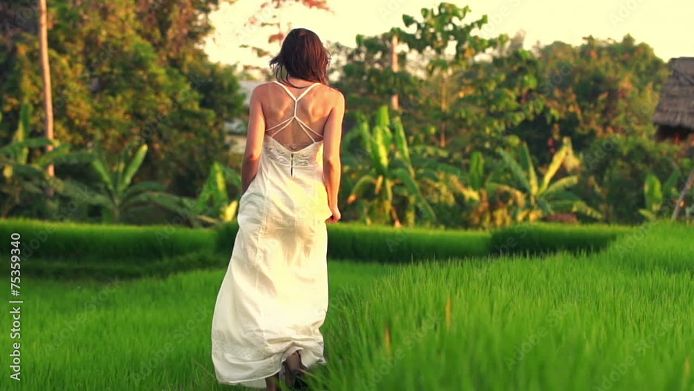 Woman in white dress walking through rice field, slow motion Woman in white dress walking through rice field, slow motion