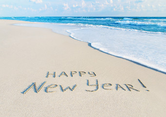 Happy New Year caption at beach sand with sea wave foam