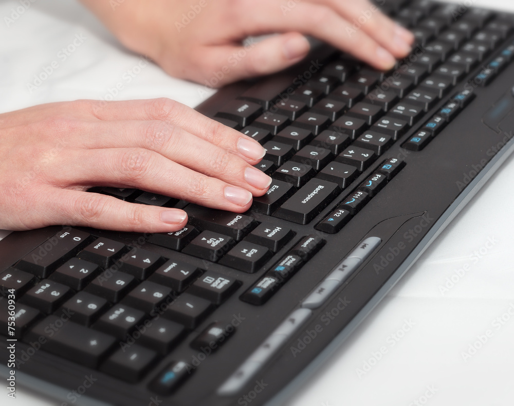Female office worker typing on a black keyboard Female office worker typing on a black keyboard