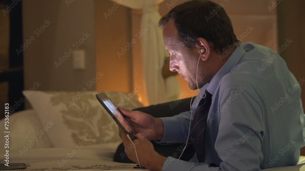 Businessman watching film on tablet computer and lying on bed at Businessman watching film on tablet computer and lying on bed at
