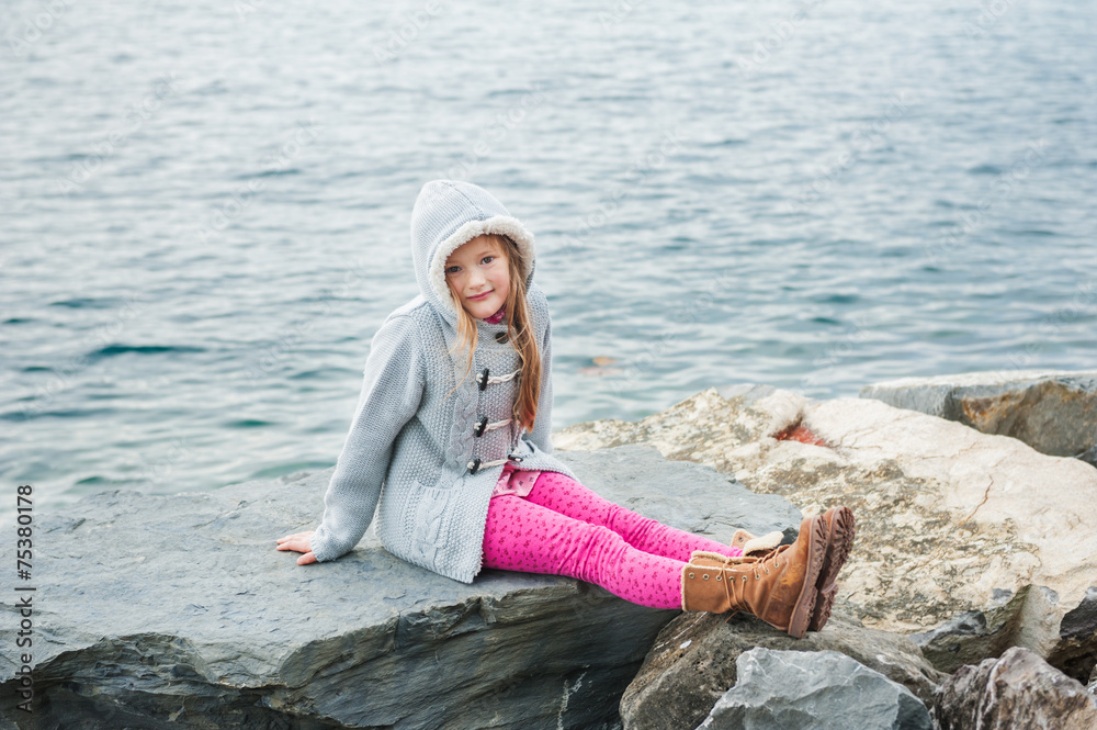 Pretty little girl resting by the lake