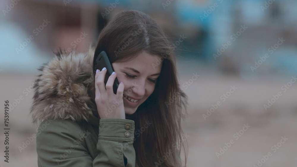 Cute girl sitting on the beach and talking on the phone Cute girl sitting on the beach and talking on the phone