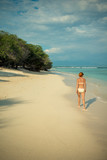 Young woman walking along tropical beach
