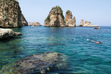 People snorkeling in front of Faraglioni at Scopello on Sicily